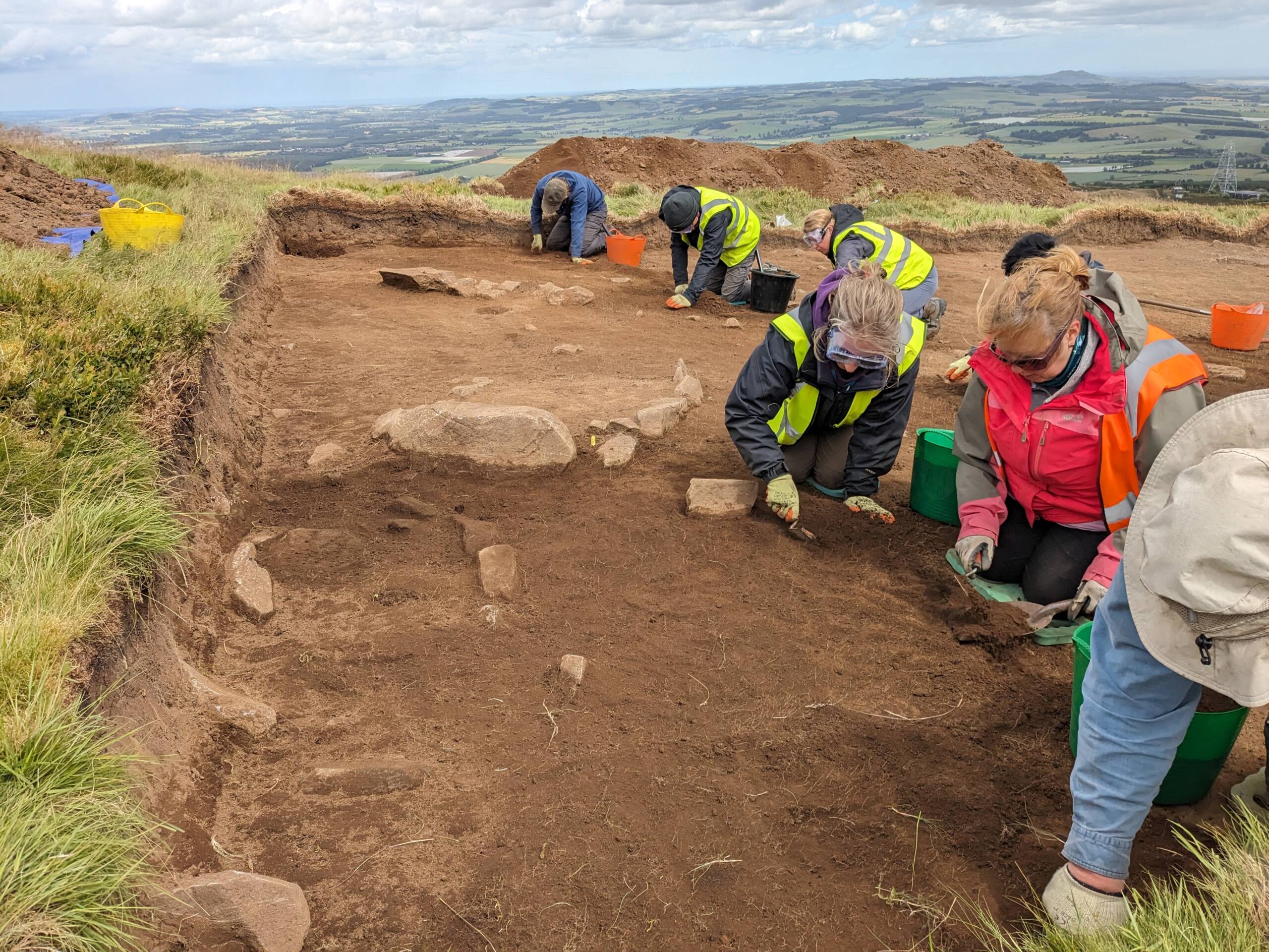 view from the hilltop as volunteers excavate a trench on East Lomond